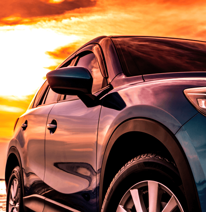 Close-up of a car against a vibrant sunset background.