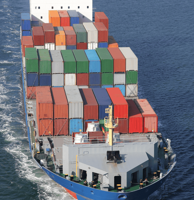 Cargo ship carrying multicolored shipping containers sailing through a waterway.