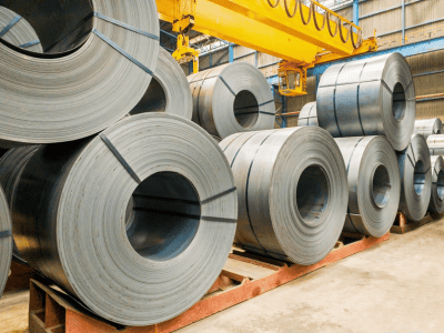 Stacks of large steel coils stored in a warehouse, ready for processing or shipment.