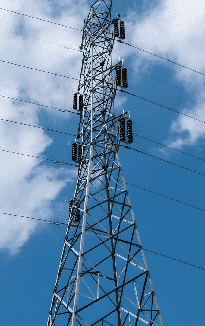 A steel transmission tower against a blue sky, showcasing the strength and height of the structure made with steel bars.